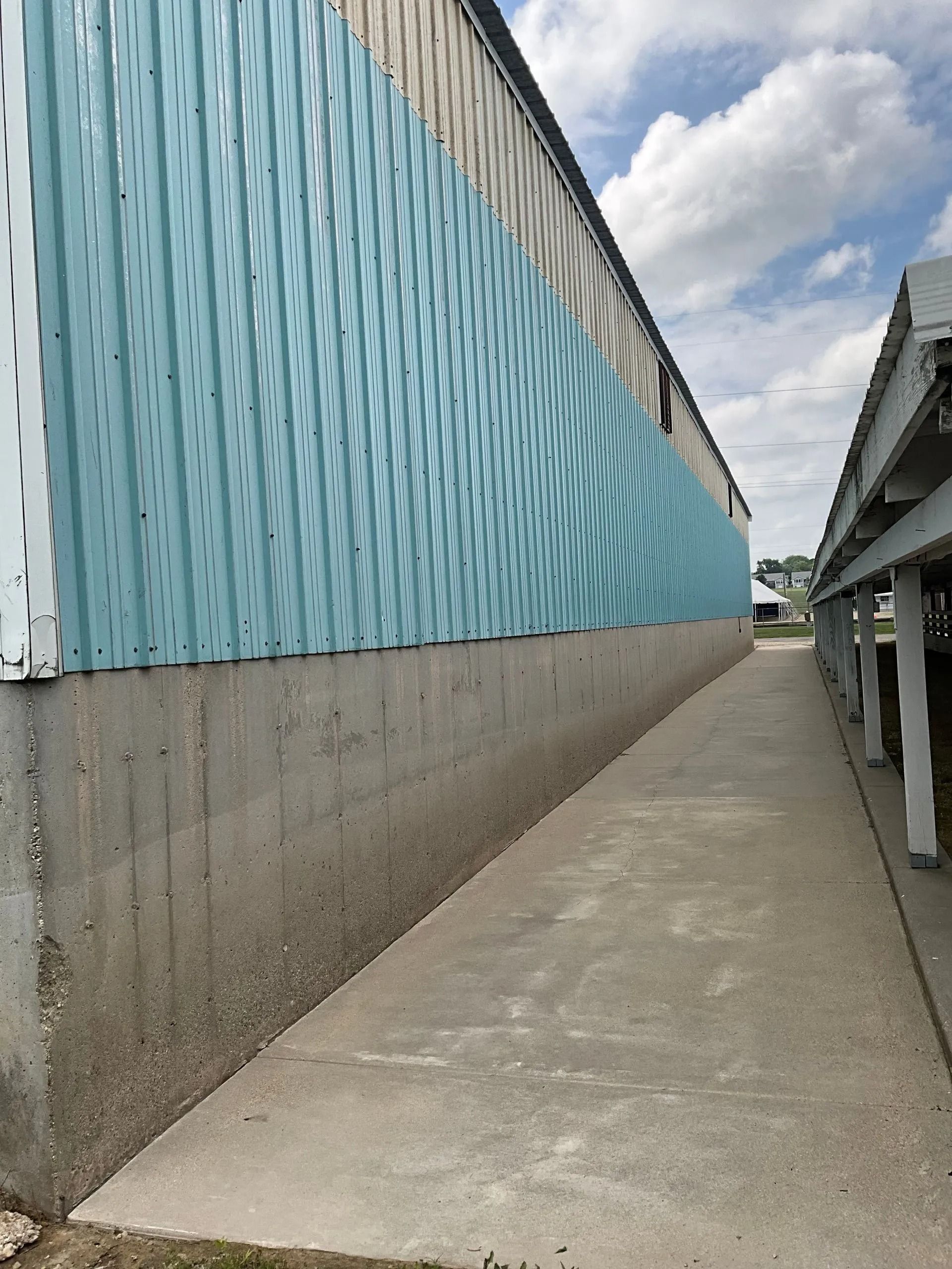 A concrete walkway leading to a building with a blue and white wall.