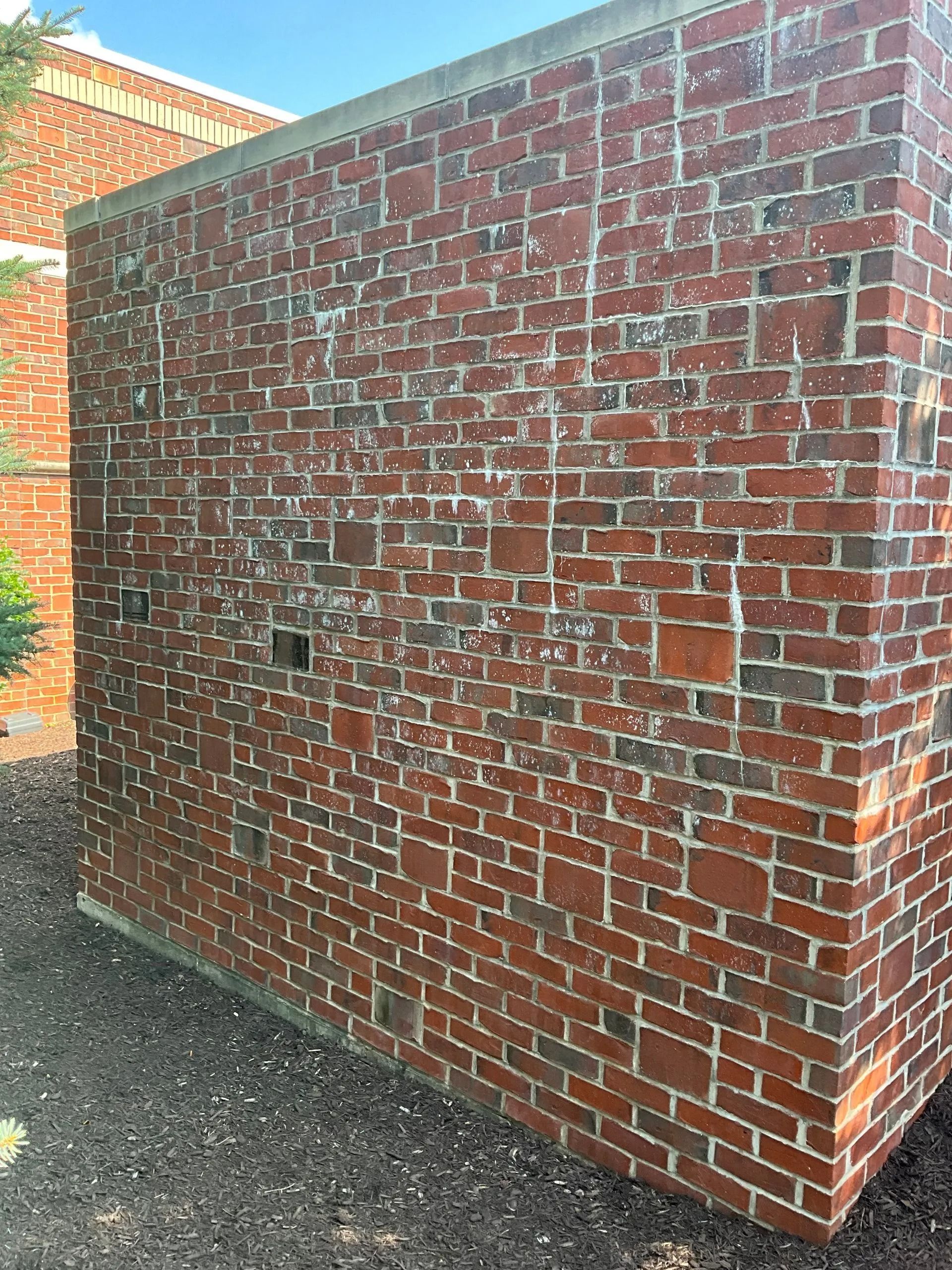 A large brick wall is sitting in front of a building.