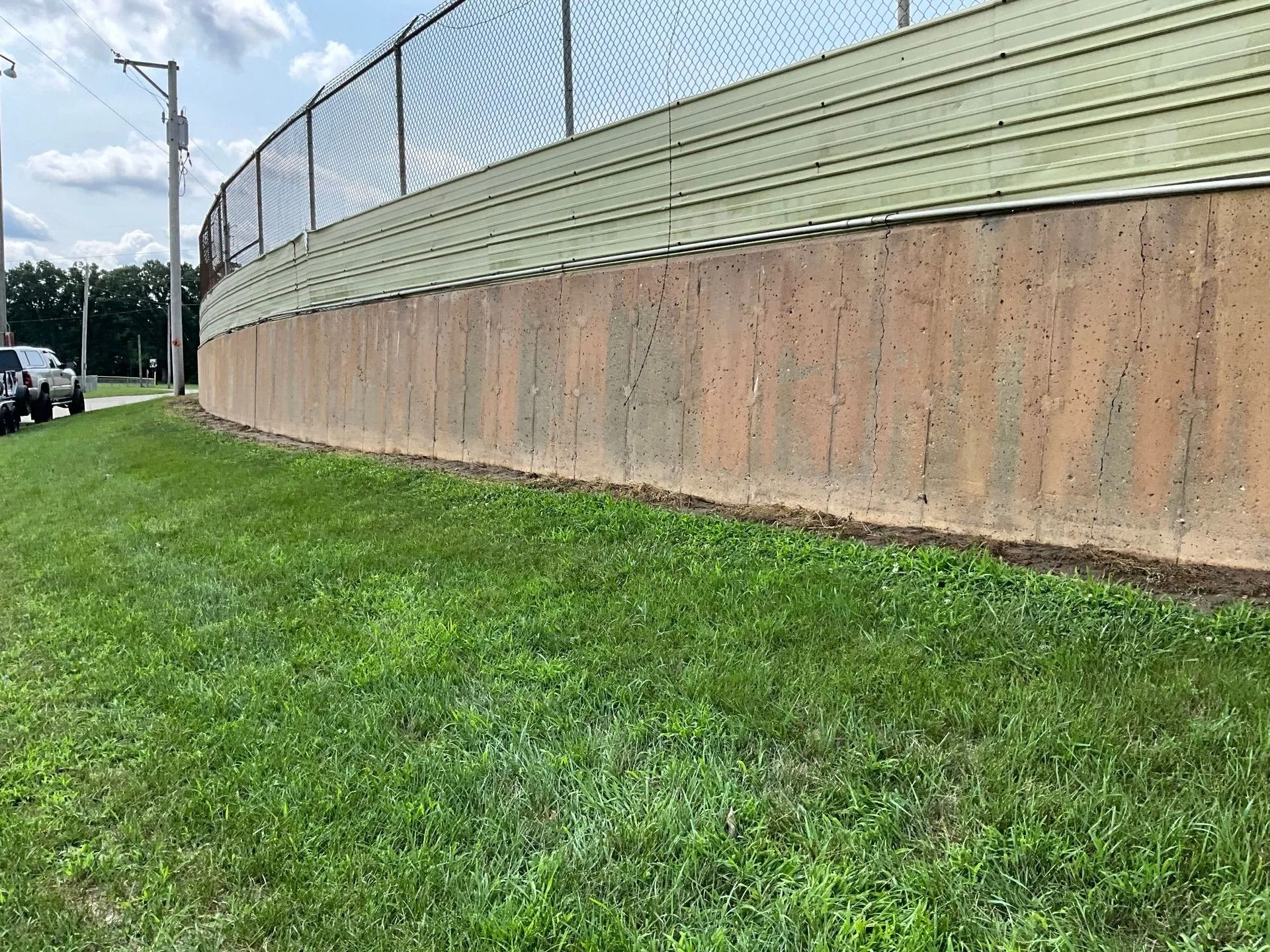 A large concrete wall with a chain link fence surrounding it.