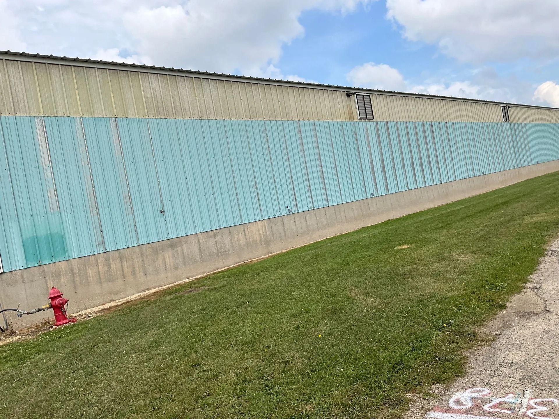 A fire hydrant is in the grass next to a fence.