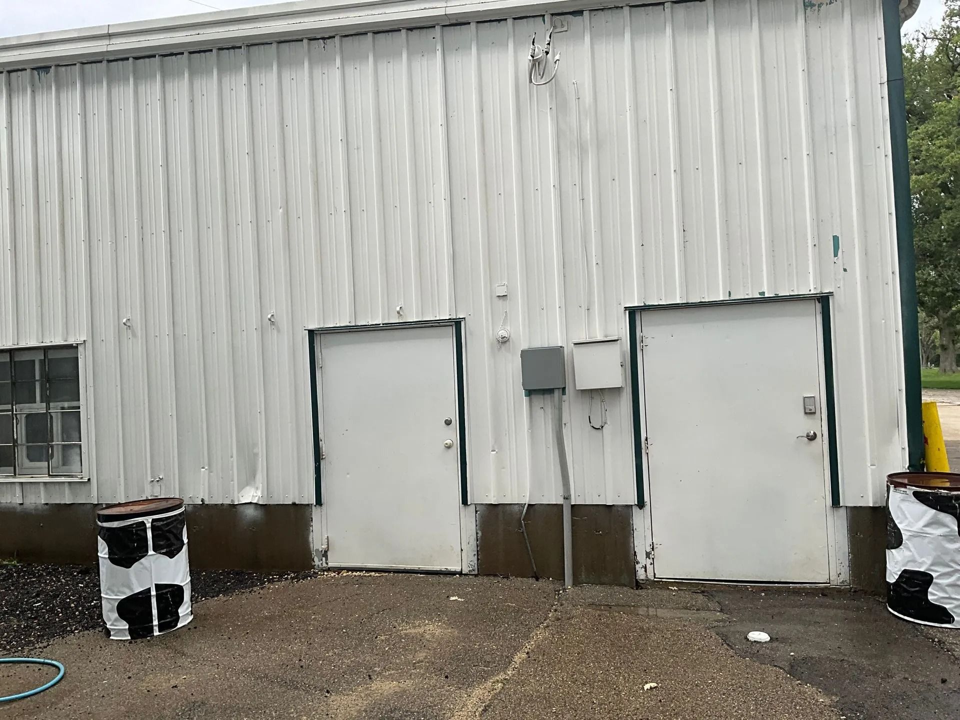 A white building with a lot of doors and a hose in front of it.