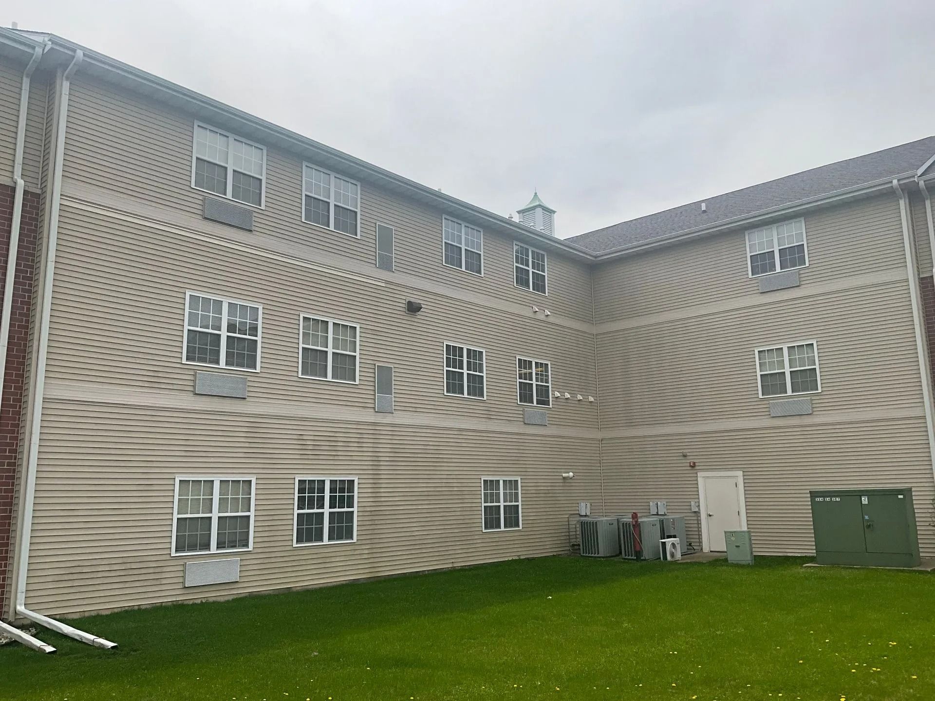 A large building with a lot of windows and a lawn in front of it.