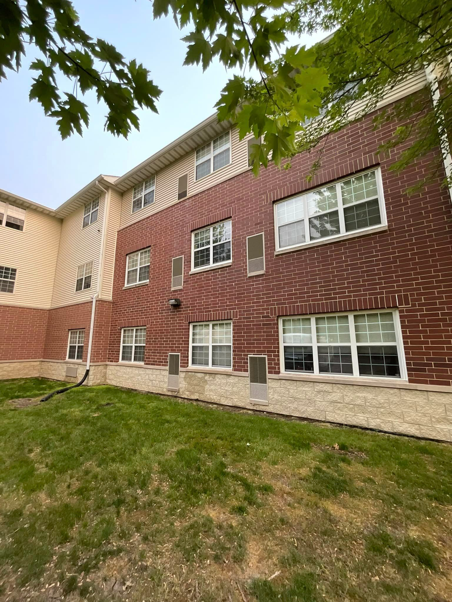 A large brick building with a lot of windows and grass in front of it.