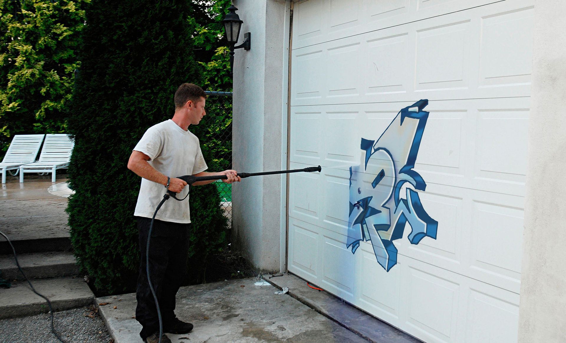 A man is cleaning a garage door with a high pressure washer