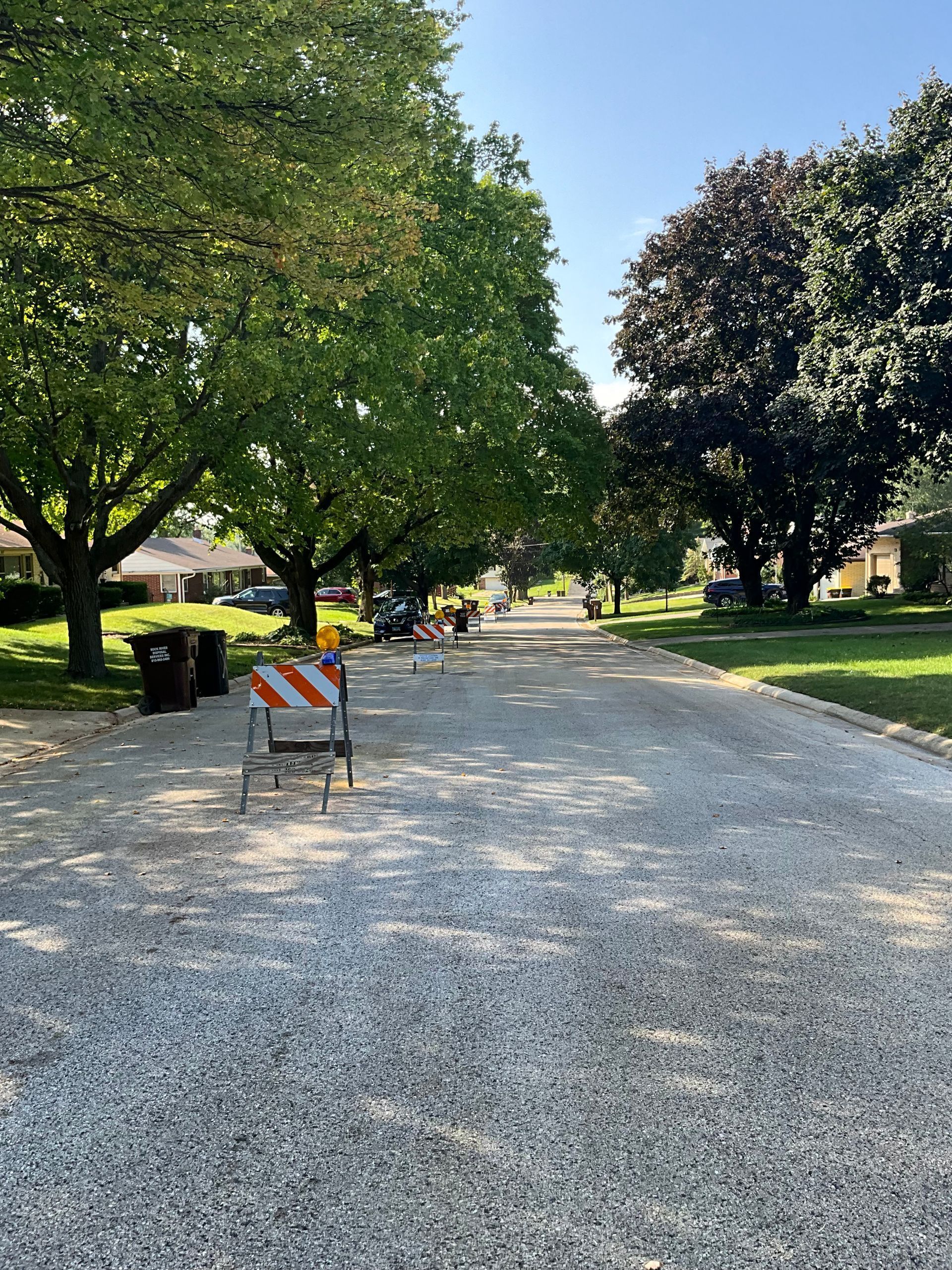 A street covered in gravel with trees and a barricade in front of a house.