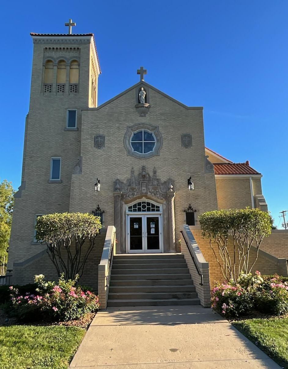 Church building with a tall brick tower, stairs, and blue sky.