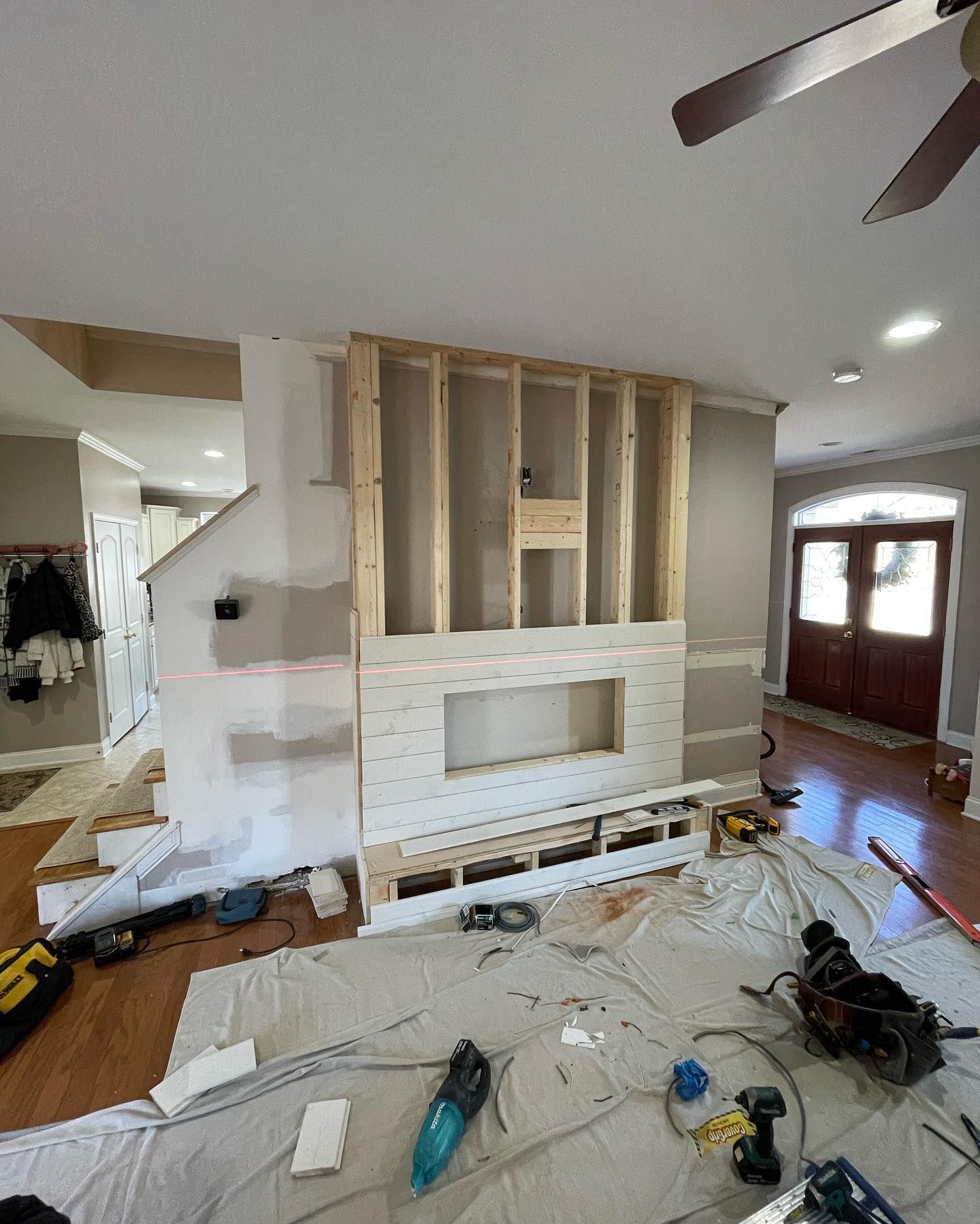 Room under construction; fireplace wall with framing, drywall, and tools scattered on floor.