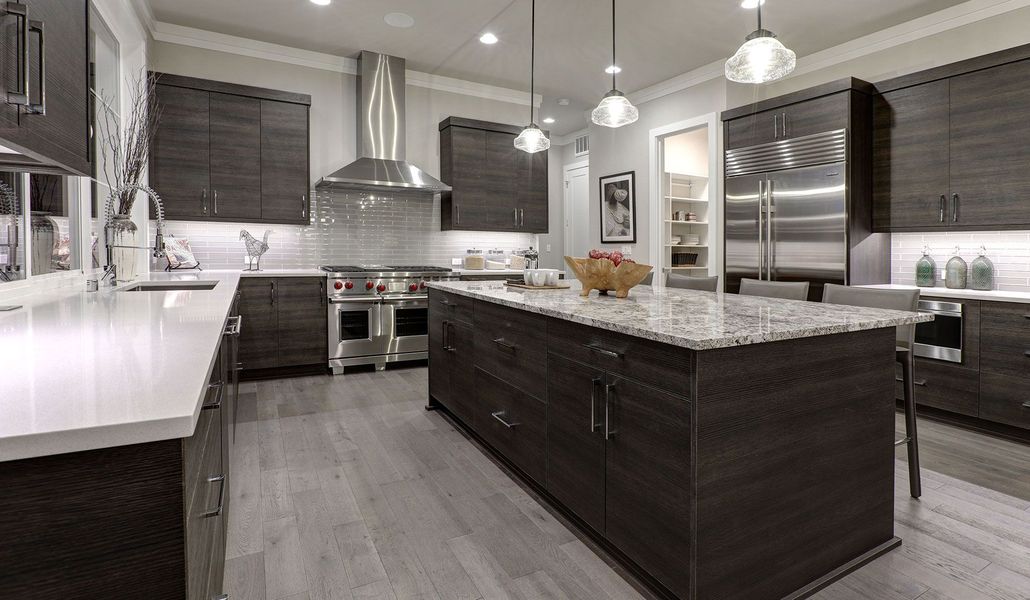 Modern kitchen with dark cabinets, marble island, stainless steel appliances, and pendant lights
