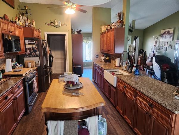 Kitchen with wooden cabinets, granite counters, and a central island in warm lighting