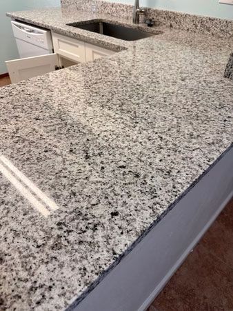Granite kitchen countertop with undermount sink and light-colored cabinets