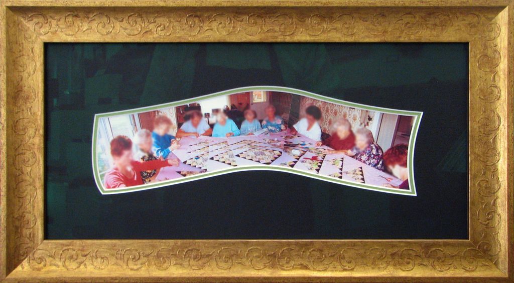 A picture of a group of people sitting at a table in a gold frame.