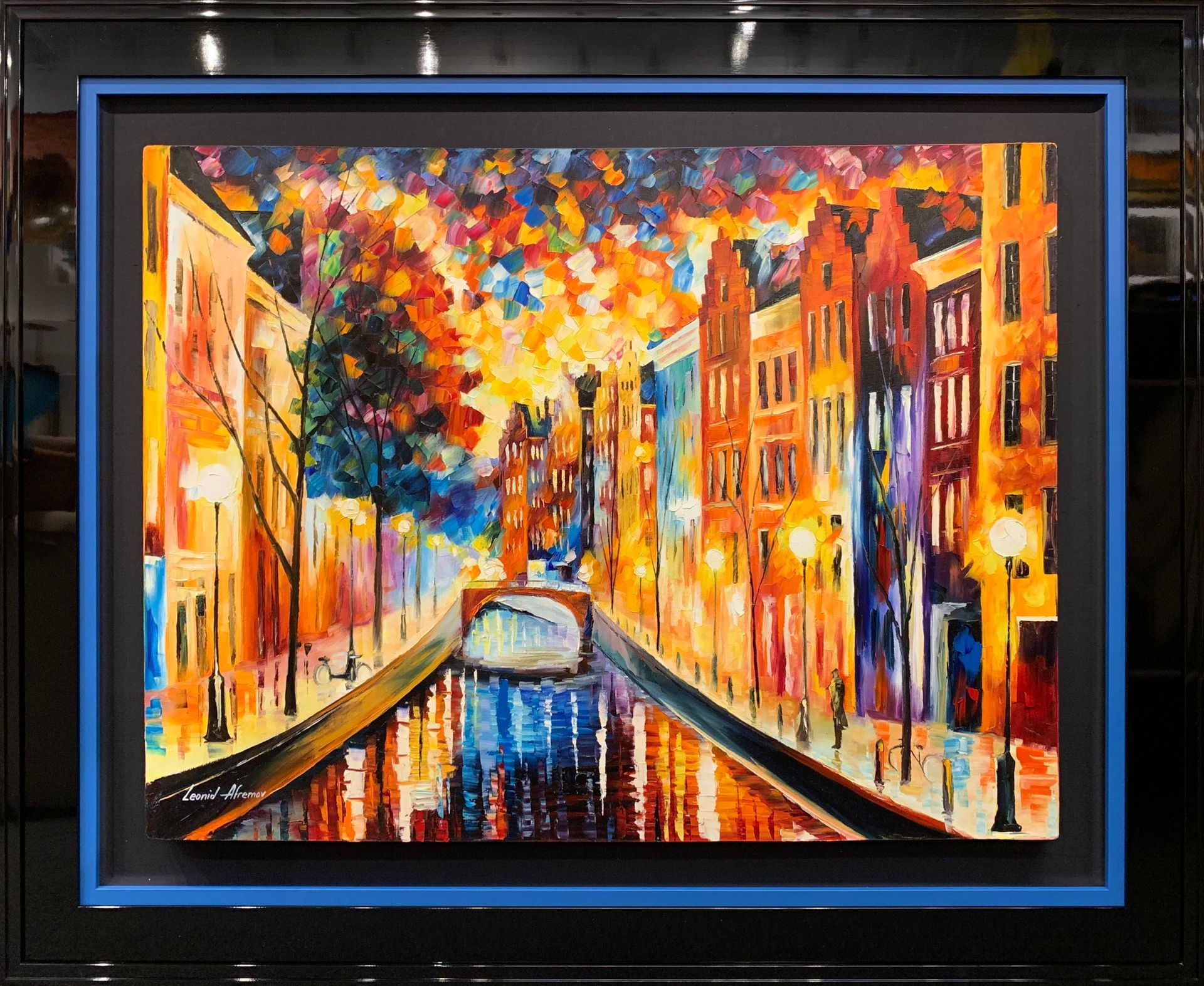 A framed painting of a city with a river running through it