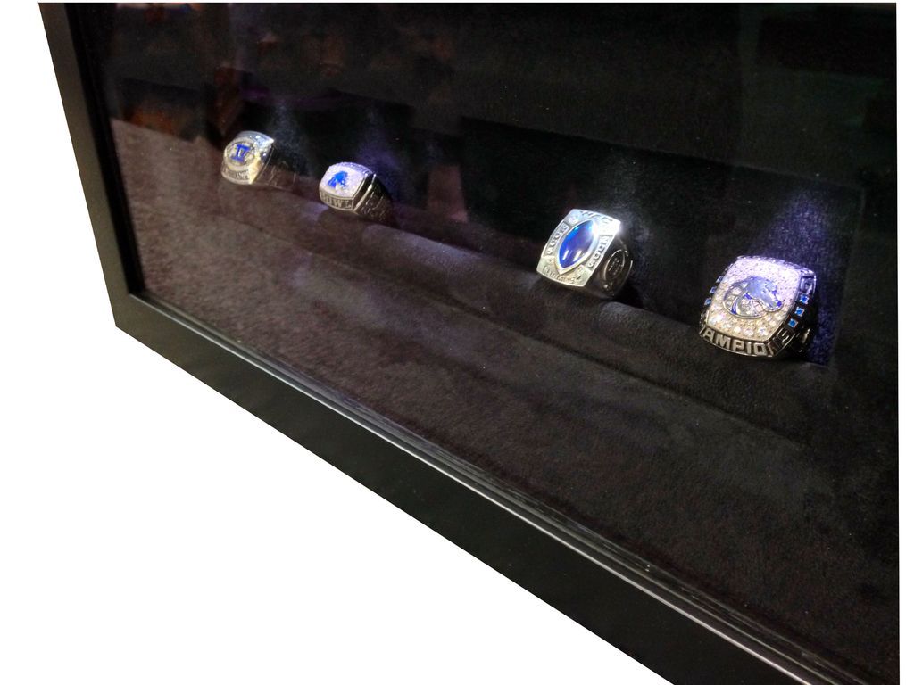 Four championship rings are displayed in a black frame