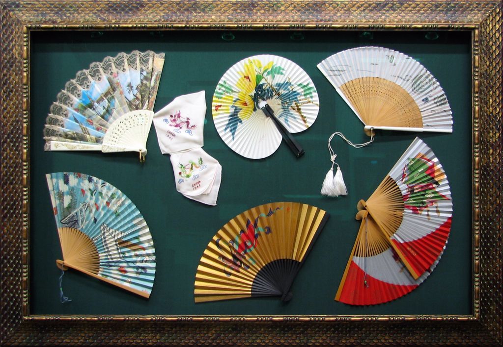 A collection of fans in a gold frame on a green background