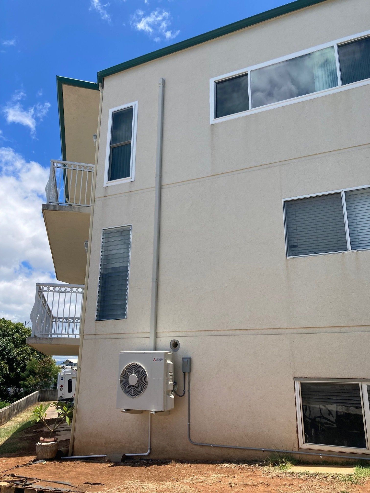 Exterior of a two-story building with an air conditioning unit attached to the wall.
