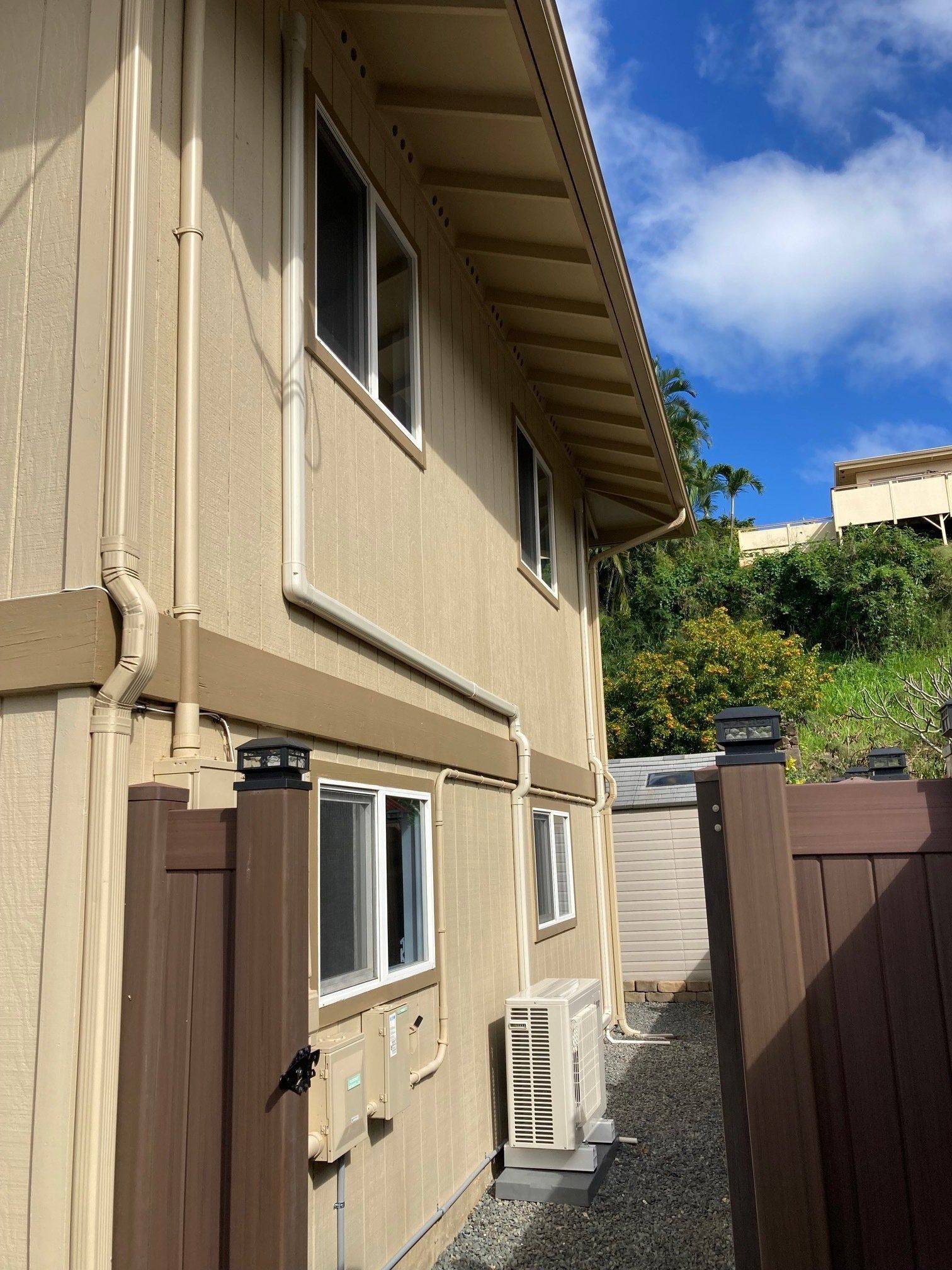 Two-story beige building with white-framed windows, brown trim, and a brown fence.