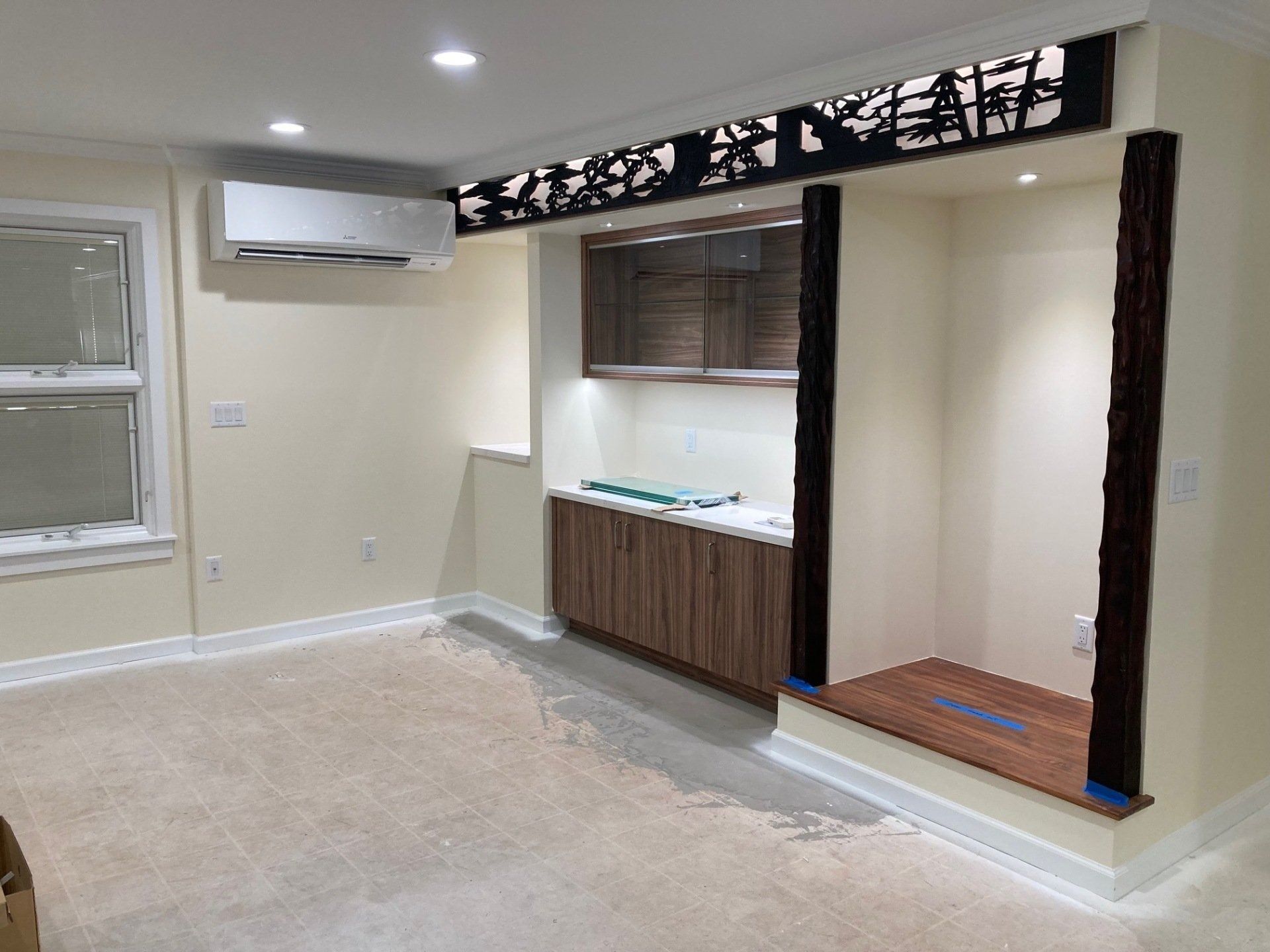 Interior view of a built-in cabinet with a decorative panel above it; air conditioner on the wall.