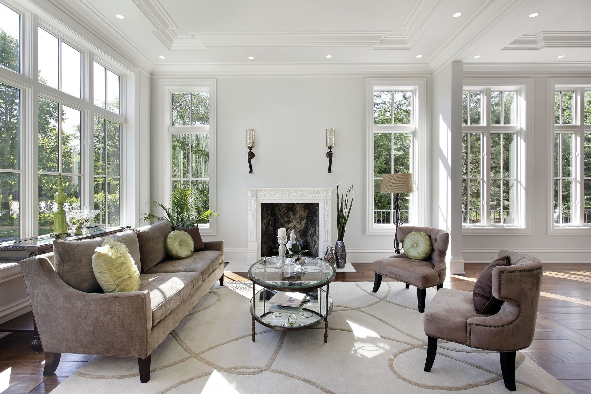 Living room with large windows, fireplace, neutral furniture, and light rug.