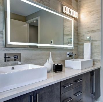 Modern bathroom with double sinks, large mirror, and gray cabinets.