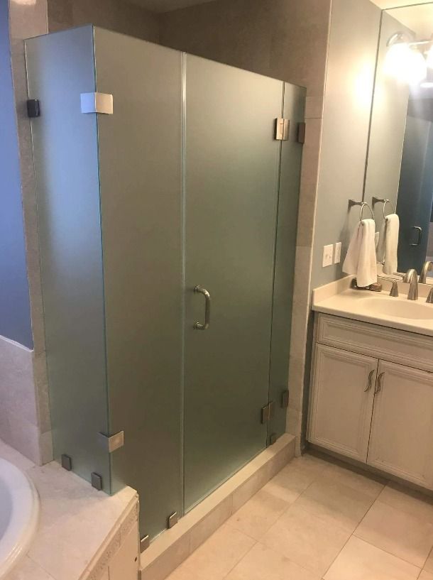 Frosted glass shower enclosure in a bathroom with a vanity and sink.