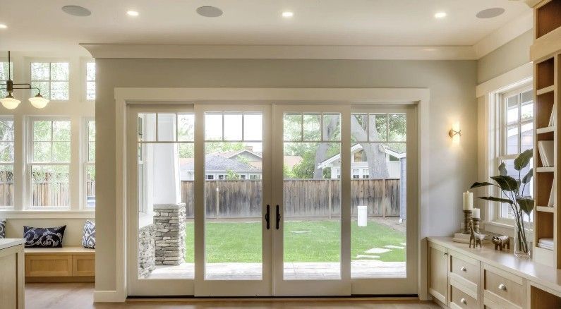 Large glass sliding doors open to a backyard with a green lawn. Interior has wood trim and neutral colors.