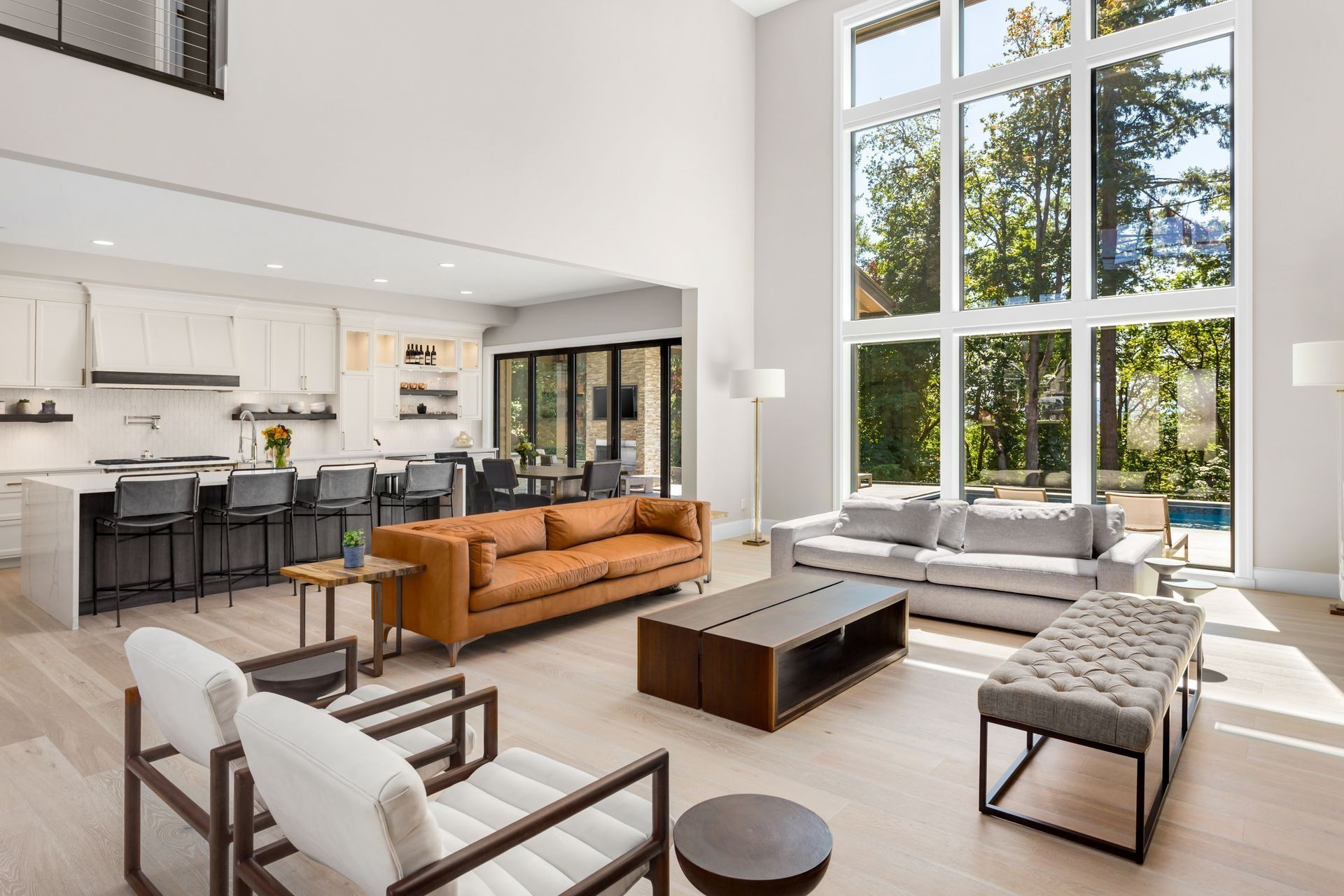 Modern living room with large windows, open kitchen, and various seating options.
