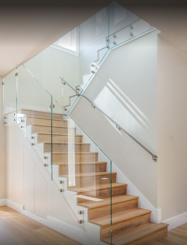 Staircase with light wood steps, glass railings, and white walls.  Stainless steel handrail.