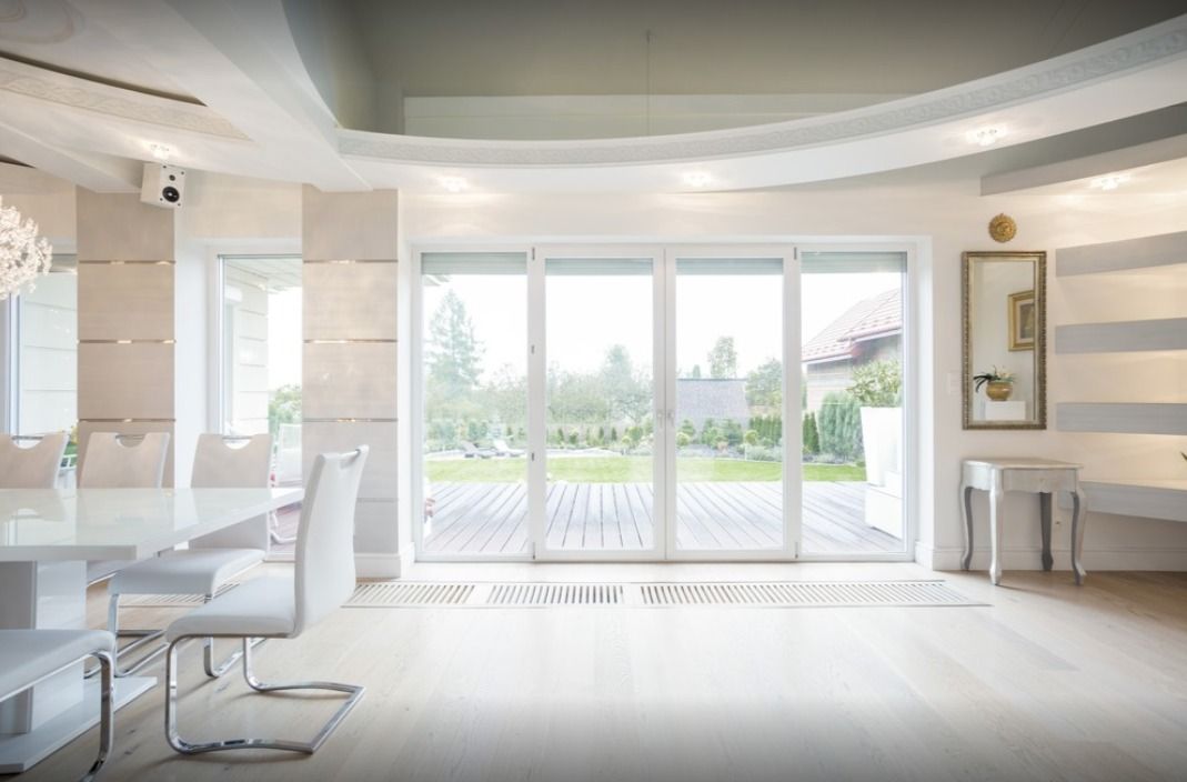 Bright white modern dining room with large glass doors overlooking a backyard.
