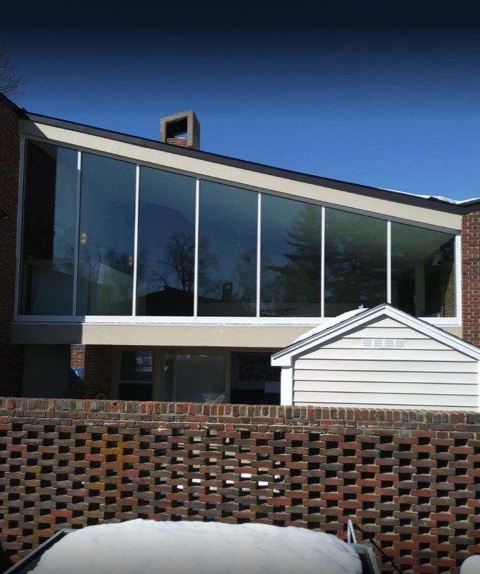 Modern house with a large glass window wall, brick facade, and snow-covered ground.