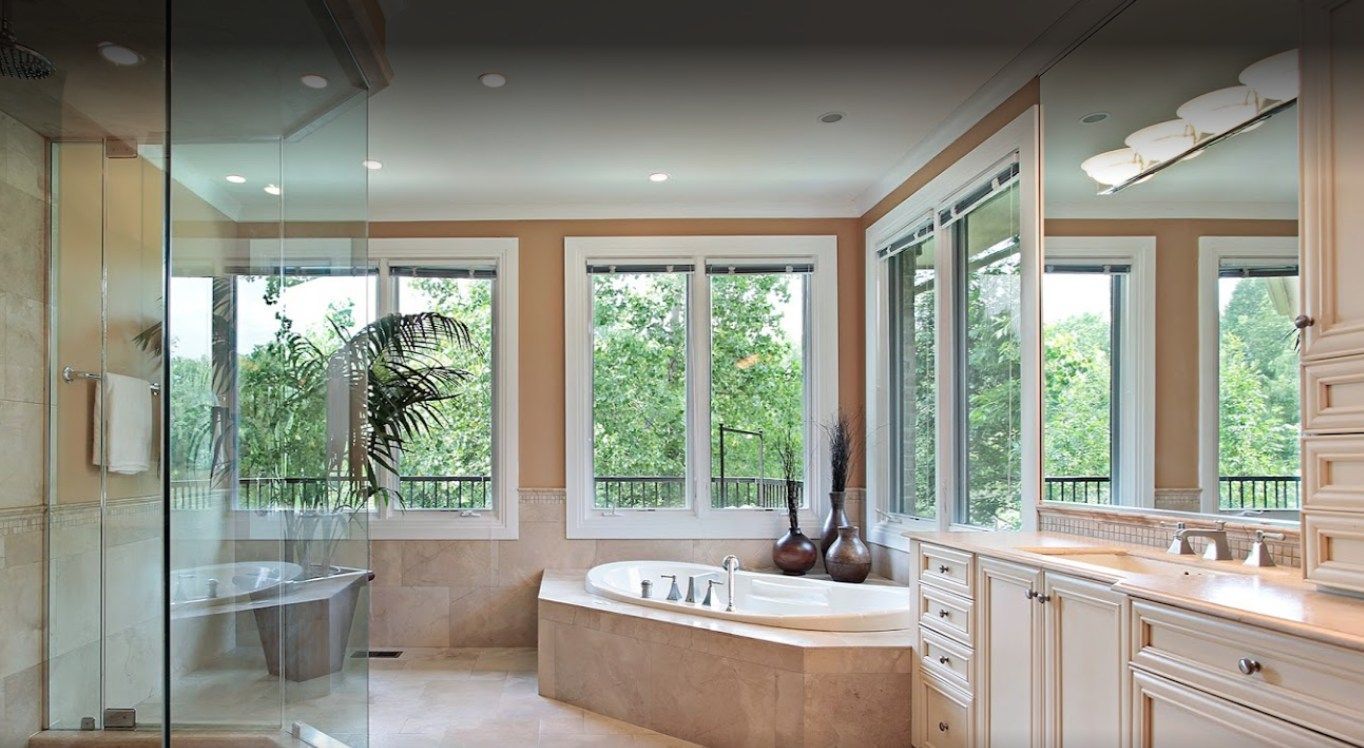 Luxurious bathroom with large windows overlooking a green forest. Features include a tub, shower, and vanity.