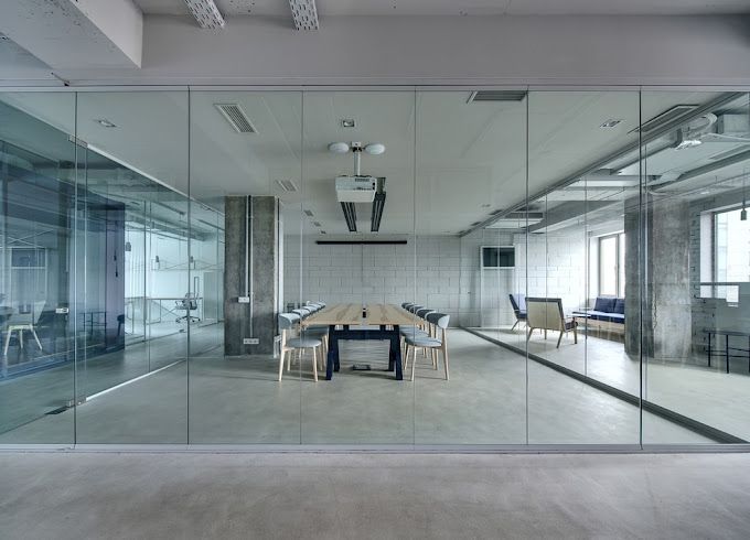 Modern office space with glass walls, conference table, and chairs.