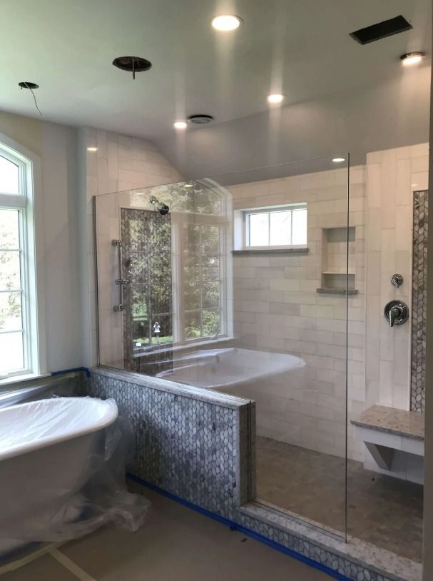 Bathroom with glass shower, soaking tub, white tile, and mosaic accents.