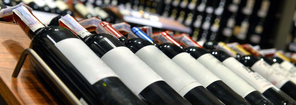 A row of wine bottles sitting on top of a wooden shelf