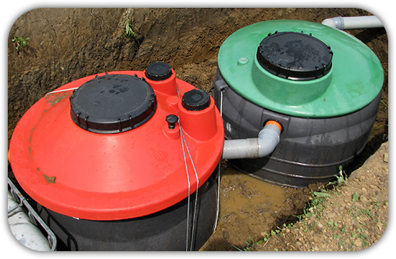 two septic tanks one red and one green are in the dirt