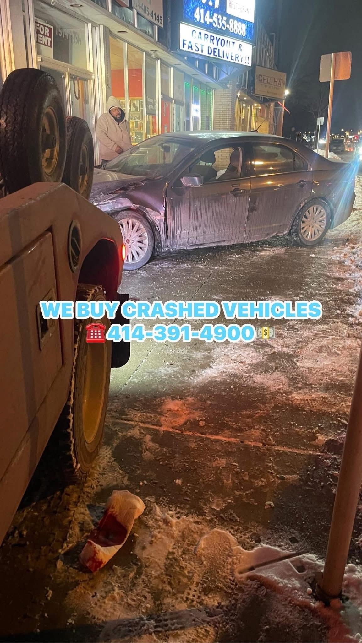 A car being towed after a crash in a snowy urban setting. Text promotes buying crashed vehicles. 