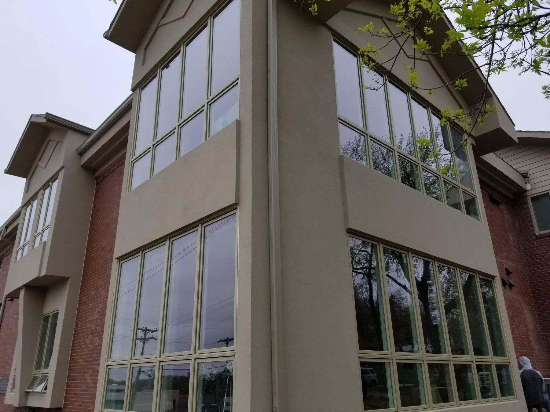 Corner view of a building with large windows and tan stucco, brick facade.