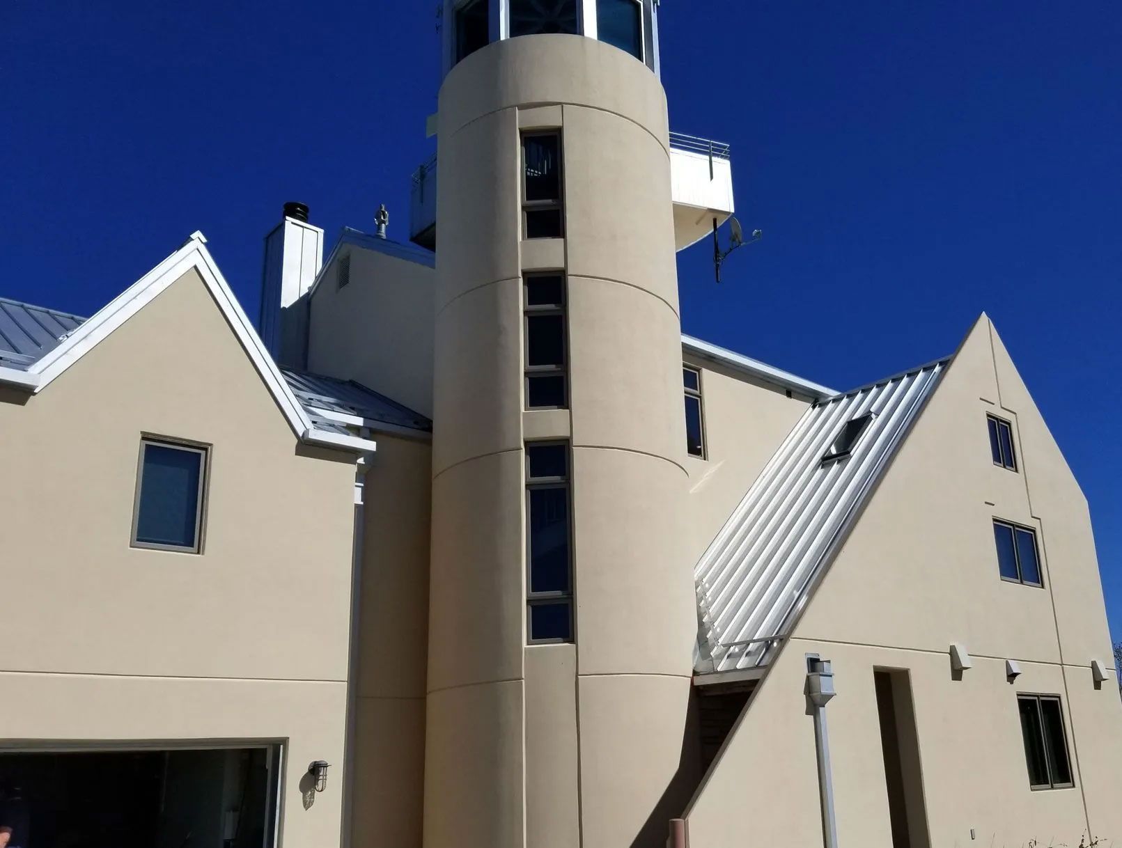 Beige building with a central cylindrical tower, multiple windows, and a blue sky background.