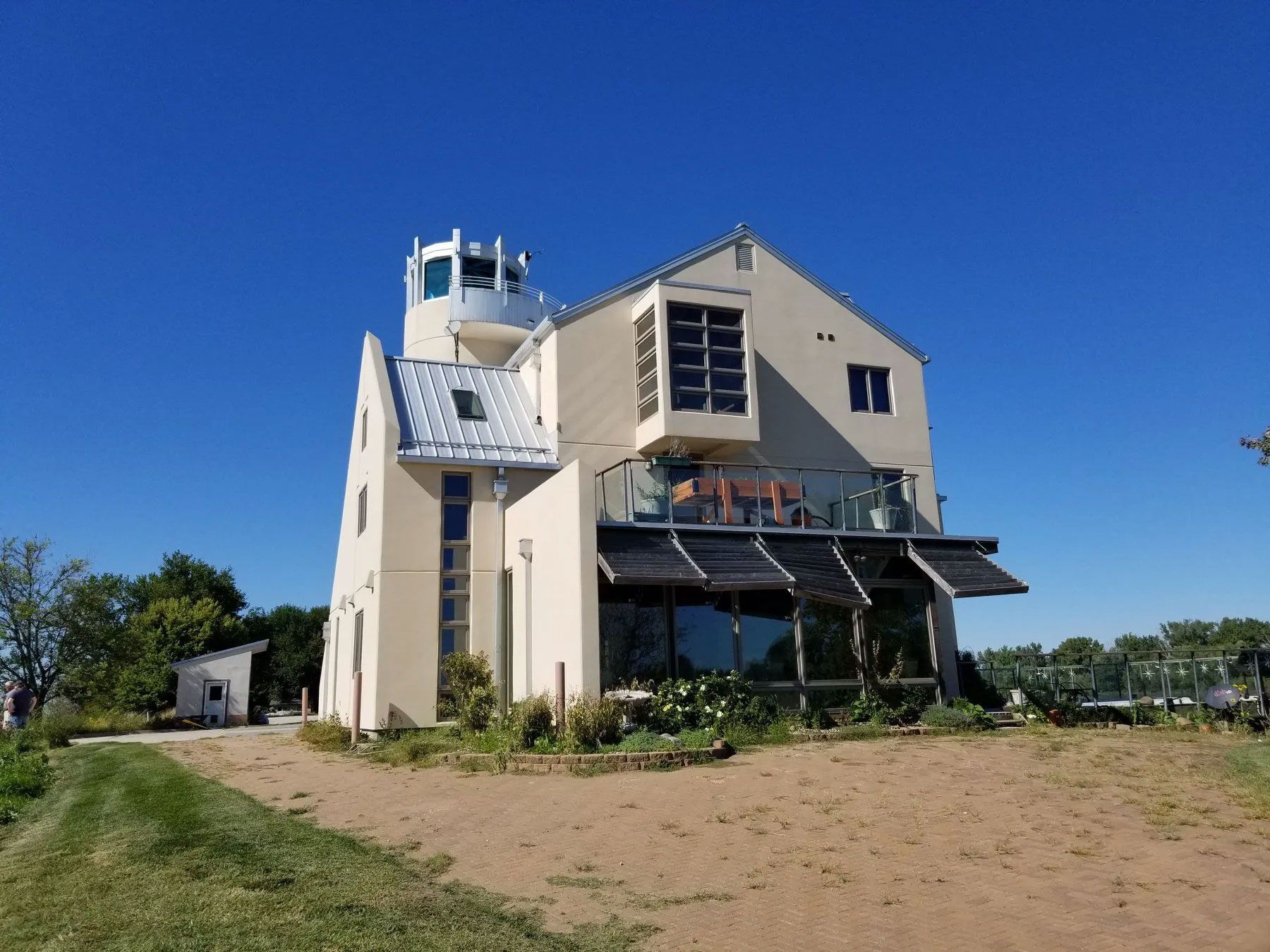 Beige, multi-story house with tower and solar panels on a sunny day.