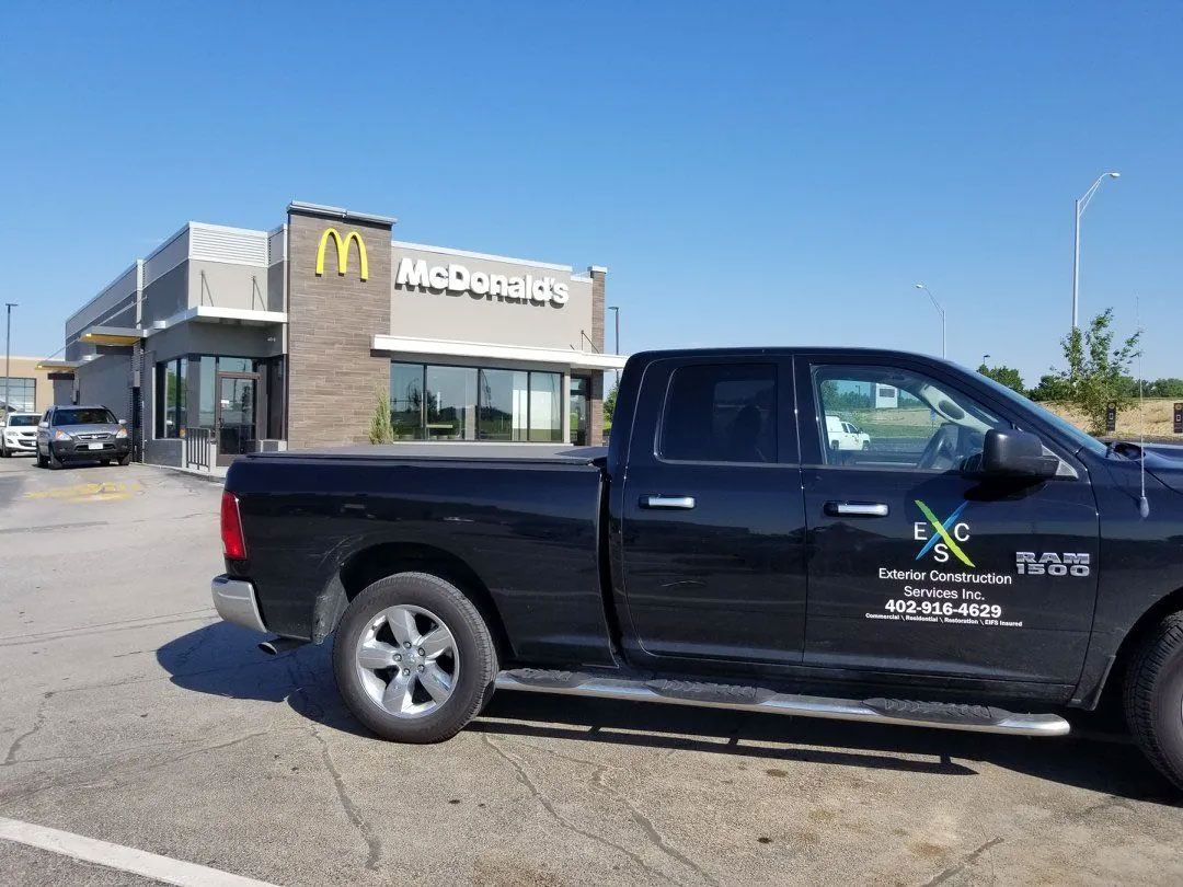 Black pickup truck parked in front of a McDonald's restaurant under a clear blue sky.