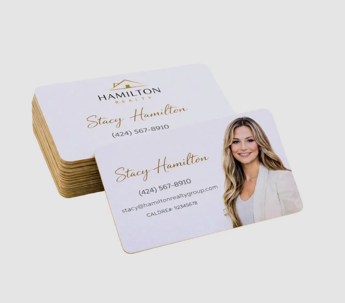 A stack of Hamilton Realty business cards featuring a contact name, phone number, and a portrait of a real estate agent.