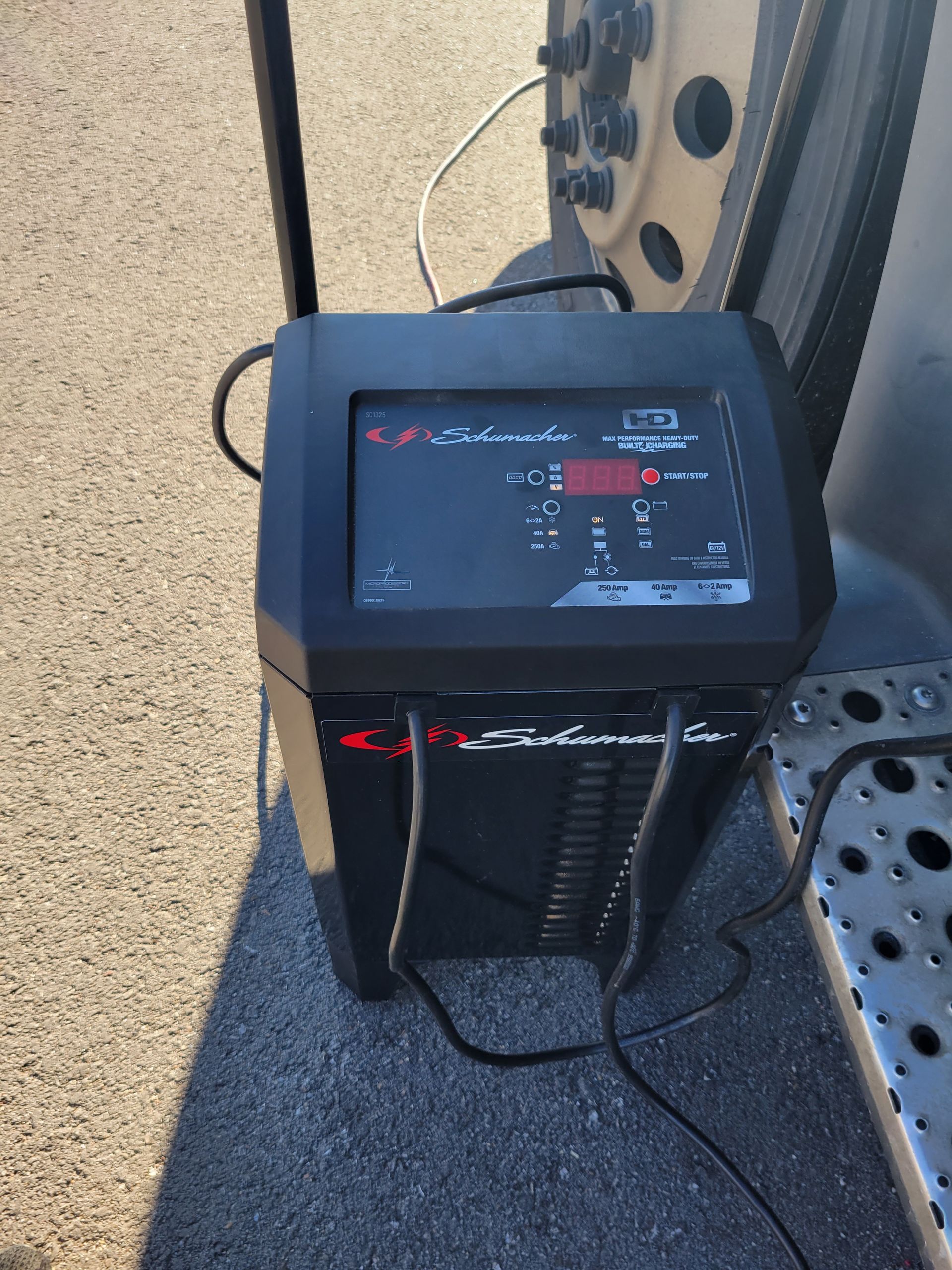 A charger is sitting on the ground next to a truck