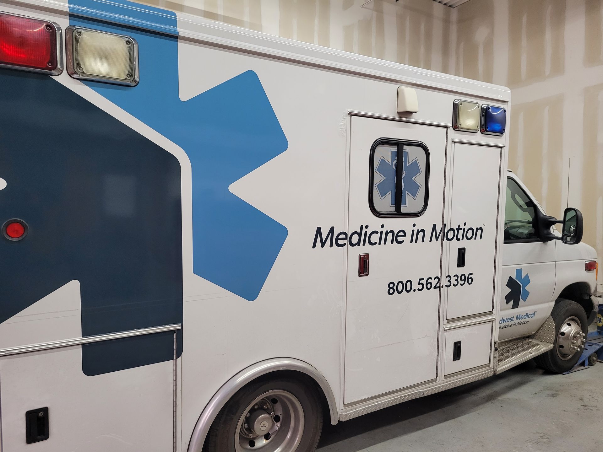 A white and blue ambulance is parked in a garage.