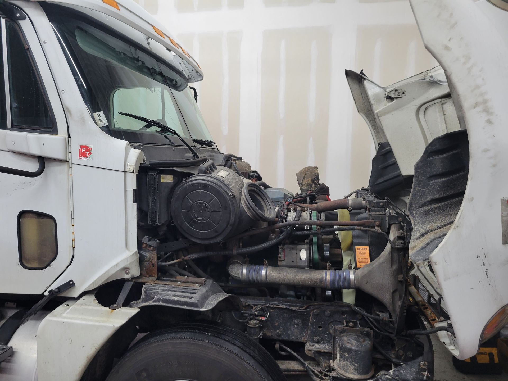 A man is working on the engine of a white truck