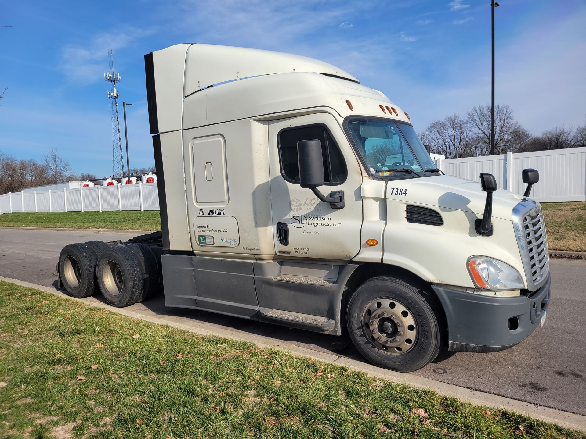 A white semi truck is parked on the side of the road.