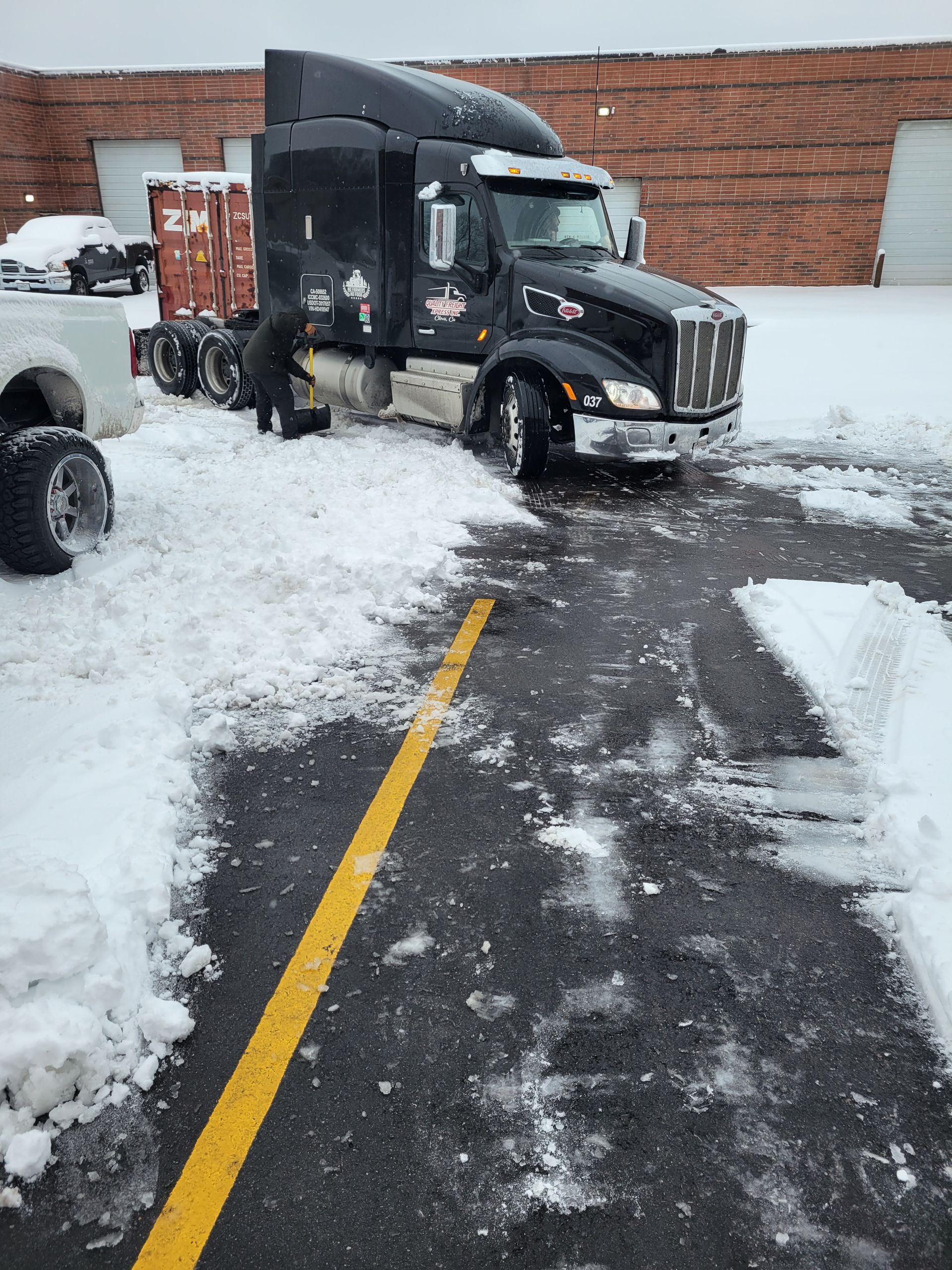 A semi truck is parked in a parking lot covered in snow.