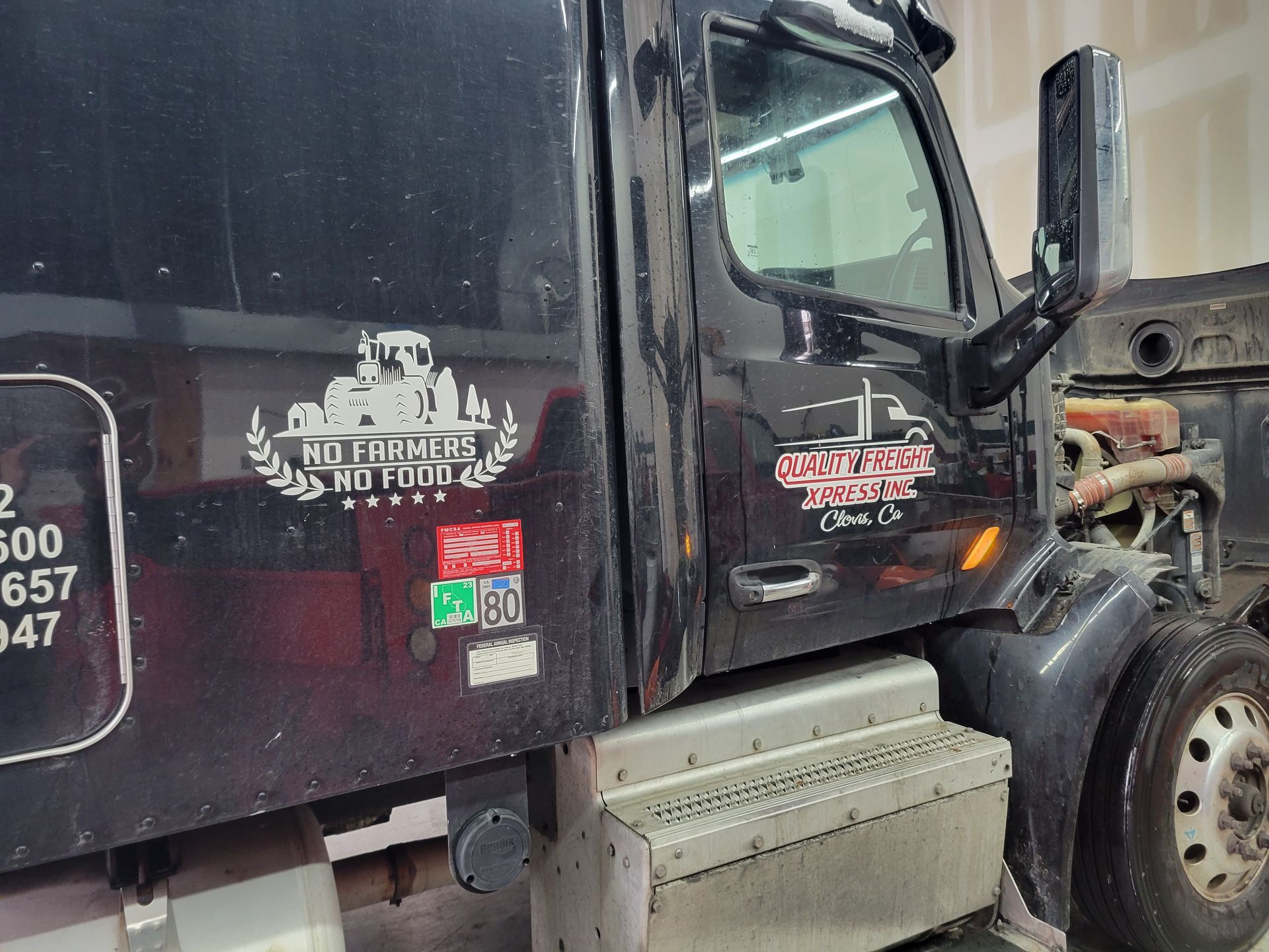 A black dump truck is parked in a garage.