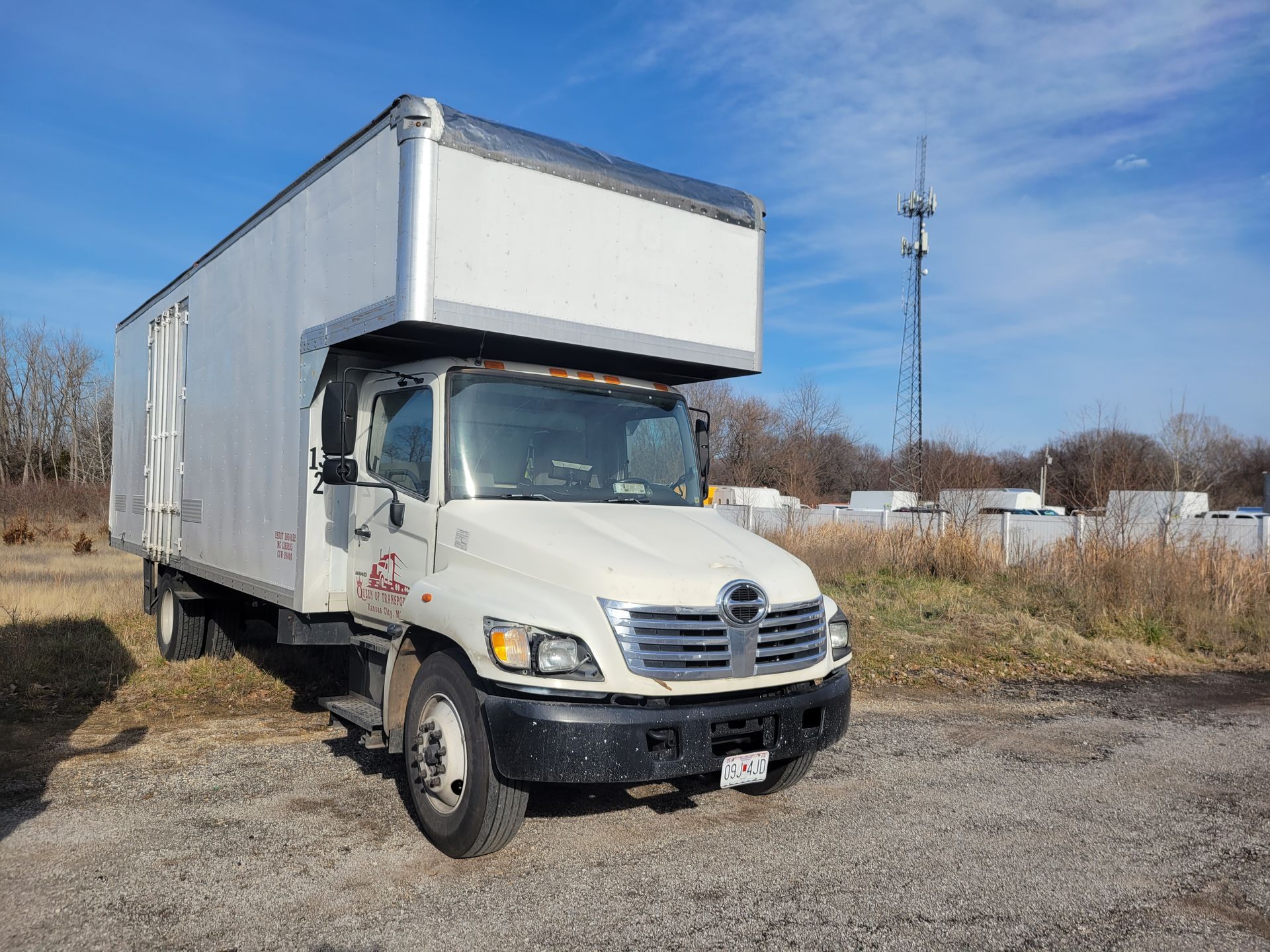 A white moving truck is parked in a gravel lot.