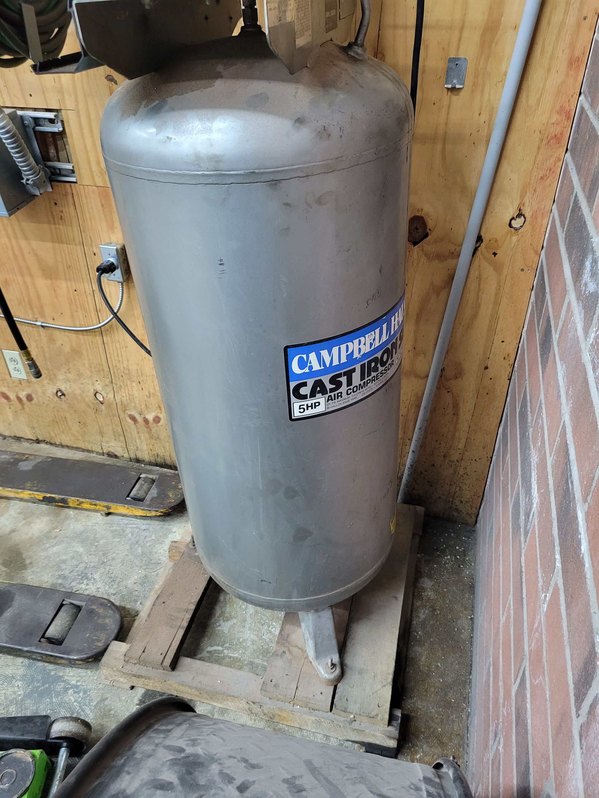 A large stainless steel tank is sitting on top of a wooden pallet.