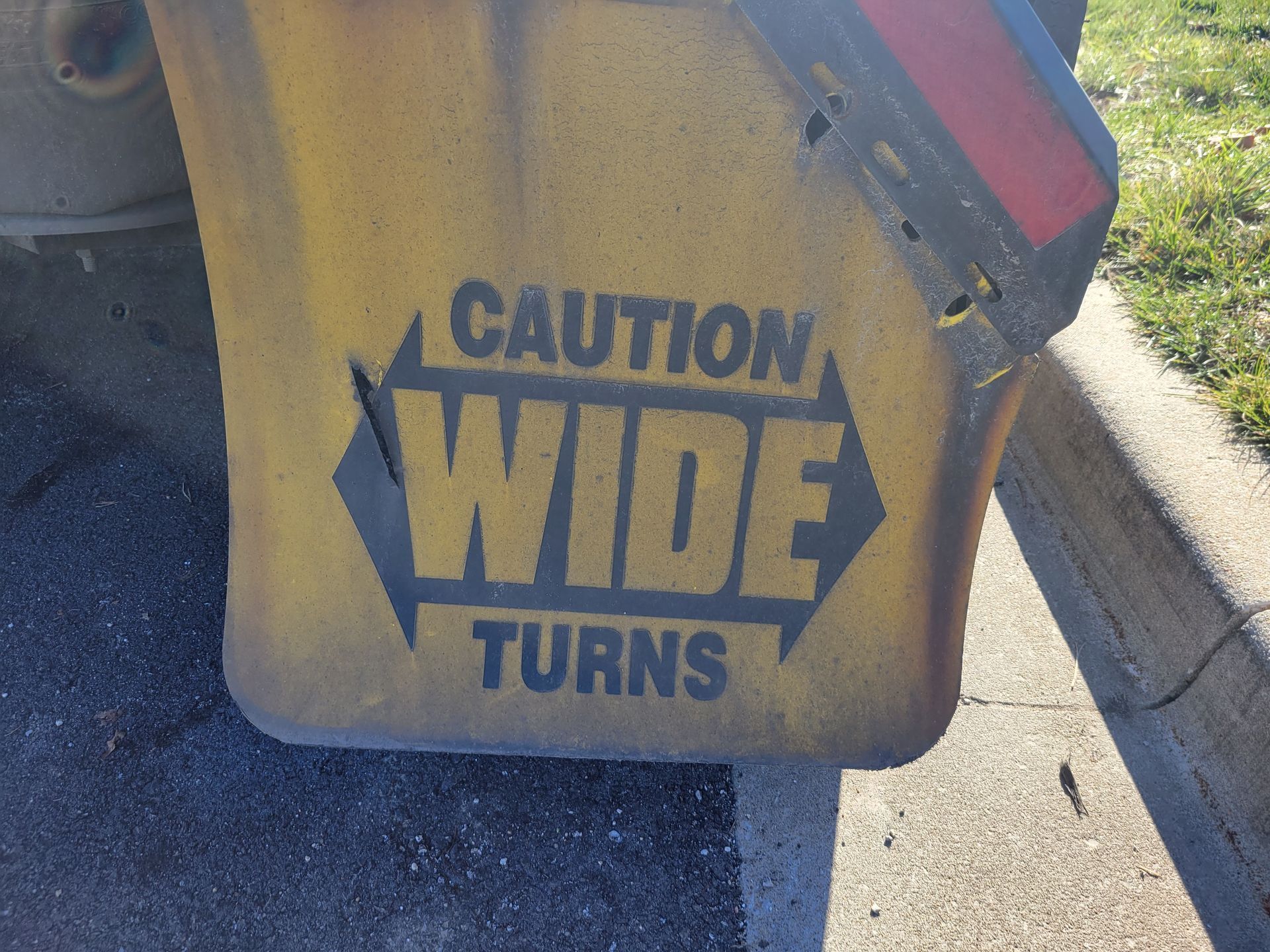 A yellow sign that says caution wide turns