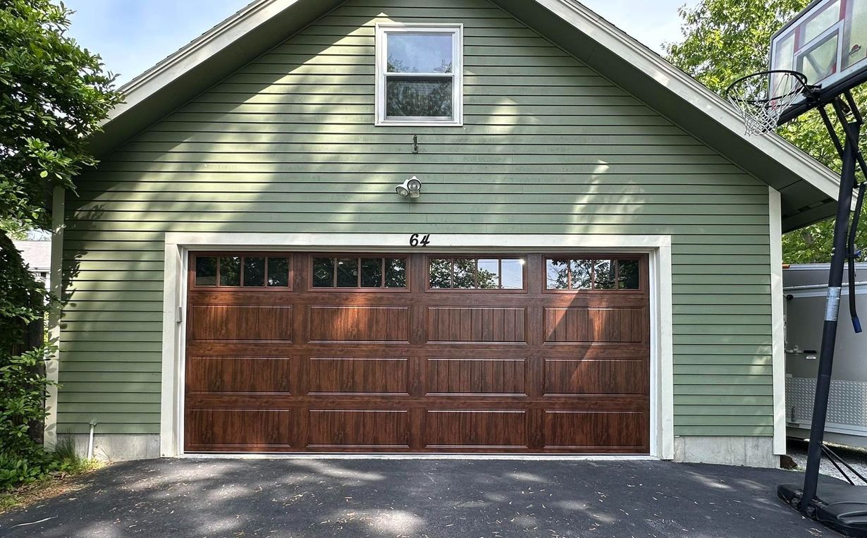 Green-sided garage with a brown garage door and a small window. Basketball hoop on the right.